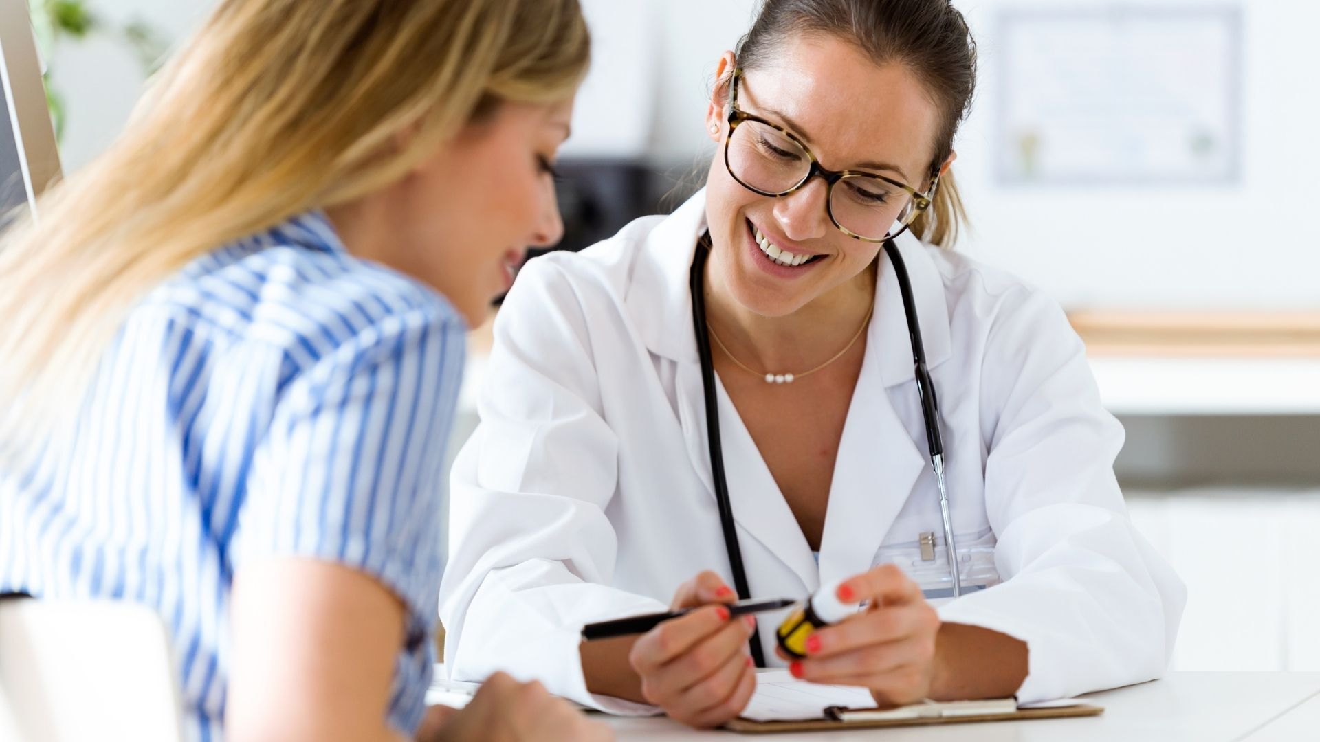 Female doctor consulting with a patient during a women’s health appointment, discussing medication and treatment options in a clinical setting.